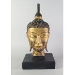 A gilt wood Buddha's head, late 20th century, on a wooden base, the head 56cm