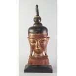 A gilt wood Buddha's head, late 20th century, on a wooden base, the head 65cm