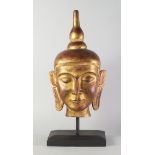 A gilt wood Buddha's head, late 20th century, on a wooden base, the head 56cm