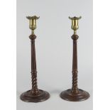 A pair of George III brass and mahogany candlesticks,