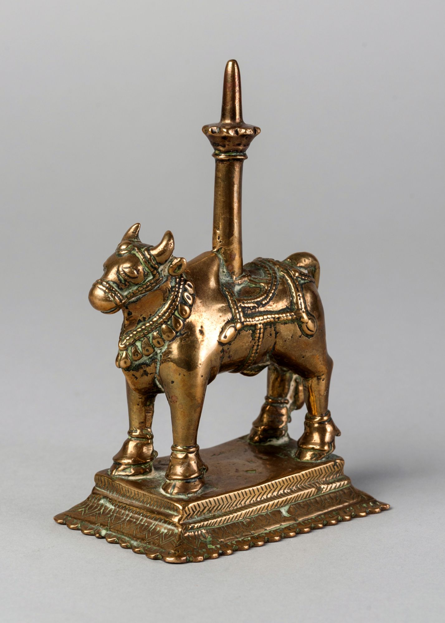 A brass votive candlestick in the form of Nandi , India, 19th century, raised on a stepped base,
