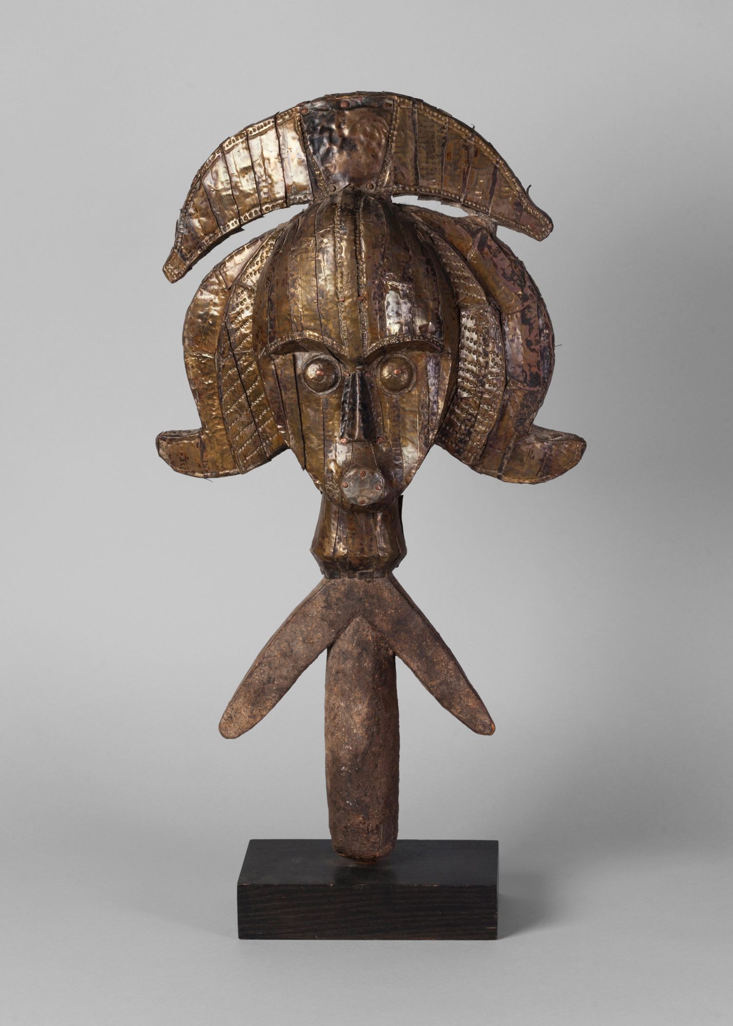 A Kota metal and hardwood carved reliquary guardian figure, wearing a crested head piece,