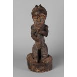 A Fang hardwood reliquary guardian figure, holding a staff in both hands, with muscled body,