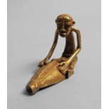 An African tribal gold figure of a seated man, his hands resting on a boat prow, Ivory Coast,