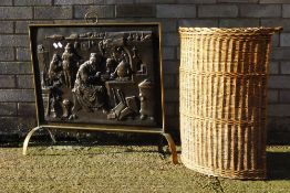 A brass and pressed copper fire guard and a wicker linen basket