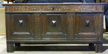 An 18th century oak three panelled coffer The hinged rectangular lid above a carved frieze over the