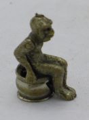 A cigar cutter in the form of a monkey sitting on a potty