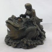 A bronze figure of a man riding a toad