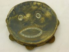 A vintage tambourine painted with a face