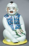 A 19th century Chinese porcelain boy Modelled seated, holding fruit and wearing a floral waistcoat.