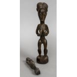 An Ivory Coast carved wooden figure of a woman Modelled holding her breasts;