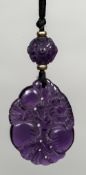 A carved amethyst pendant Worked with fruiting sprays below a similarly carved bead. 6.