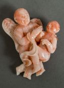 A carved coral carving Depicting an angel carrying a child. 6.25 cm high.