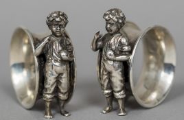 A pair of silver plated napkin rings Each modelled with a standing child. Each 6 cm high.