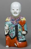 An 18th/19th century Chinese porcelain figure Modelled as a young boy kneeling holding a ruyi