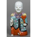 An 18th/19th century Chinese porcelain figure Modelled as a young boy kneeling holding a ruyi