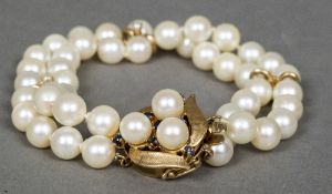 A 14 K gold and sapphire mounted pearl two strand bracelet 19 cm long.