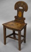 A 19th century mahogany hall chair The florally carved and inlaid shaped back above the inlaid