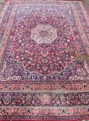 A Tabriz wool carpet The wine red field enclosing a central ivory medallion with pendant palmettes