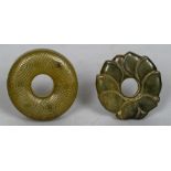 A Chinese carved jade roundel Worked as a lotus flower; together with another geometrically carved.