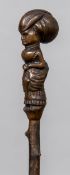 A 19th century treen Folk Art walking stick The handle carved as a well-dressed woman holding an