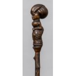 A 19th century treen Folk Art walking stick The handle carved as a well-dressed woman holding an