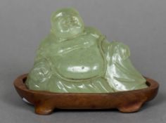 A Chinese carved hardstone model of Buddha Modelled seated, mounted on a carved wooden plinth base.