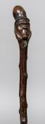 A Victorian single piece carved wooden walking stick The handle formed as a gentleman wearing a top