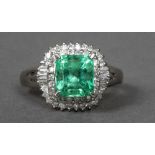 A platinum natural Columbian emerald and diamond set cluster ring The central emerald cut stone