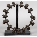 The Titcar Tribe of Cameroon, a ring of patinated bronze figural masks Approximately 32 cm diameter.