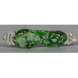 An unmarked white metal diamond set jade mounted brooch The central panel carved and pierced with