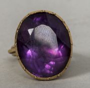 A 19th century amethyst set unmarked gold ring The stone oval cut, the band with beaded edge.