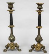 A pair of 19th century patinated and gilt bronze candlesticks Each with cast scrolling and figural