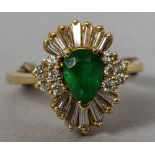 An 18 ct gold diamond and emerald set cluster ring The central stone pear cut.