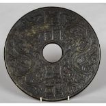 A large Chinese carved green and russet jade bi disc Carved with dragons flanking calligraphic text.