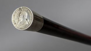 An unmarked white metal mounted hardwood walking stick The handle inset with a South African coin.