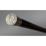 An unmarked white metal mounted hardwood walking stick The handle inset with a South African coin.