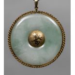 A Chinese unmarked yellow metal mounted carved jade pendant The central boss with calligraphic