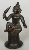 An antique Indian patinated bronze model of a deity Modelled seated, holding a club. 12 cm high.