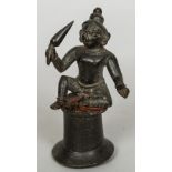 An antique Indian patinated bronze model of a deity Modelled seated, holding a club. 12 cm high.