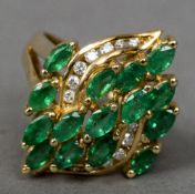 A 14 K gold emerald and diamond ring Of navette cluster form. 2.5 cm high.