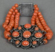 An unmarked silver mounted coral bracelet The pierced scroll work central sections set with coral