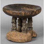 An African carved wooden tribal stool The dished seat supported by four figural columns above a