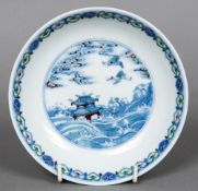 A Chinese Wucai porcelain dish The interior decorated with cranes above a pagoda amongst waves,