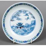 A Chinese Wucai porcelain dish The interior decorated with cranes above a pagoda amongst waves,