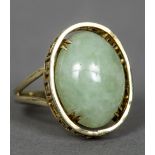 A 14 ct gold and jade ring The central jade cabochon set in a pierced Greek key border. 2 cm high.