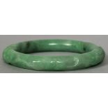 A Chinese carved green jade bangle 8 cm diameter.