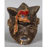 An African carved wooden tribal mask Modelled as a human face with section of applied headdress and