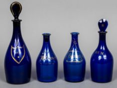 Four 19th century Bristol blue glass spirit bottles Each heightened with gilt decorations,