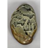 A Chinese carved green and russet jade boulder Worked with figures before pagodas in a mountainous